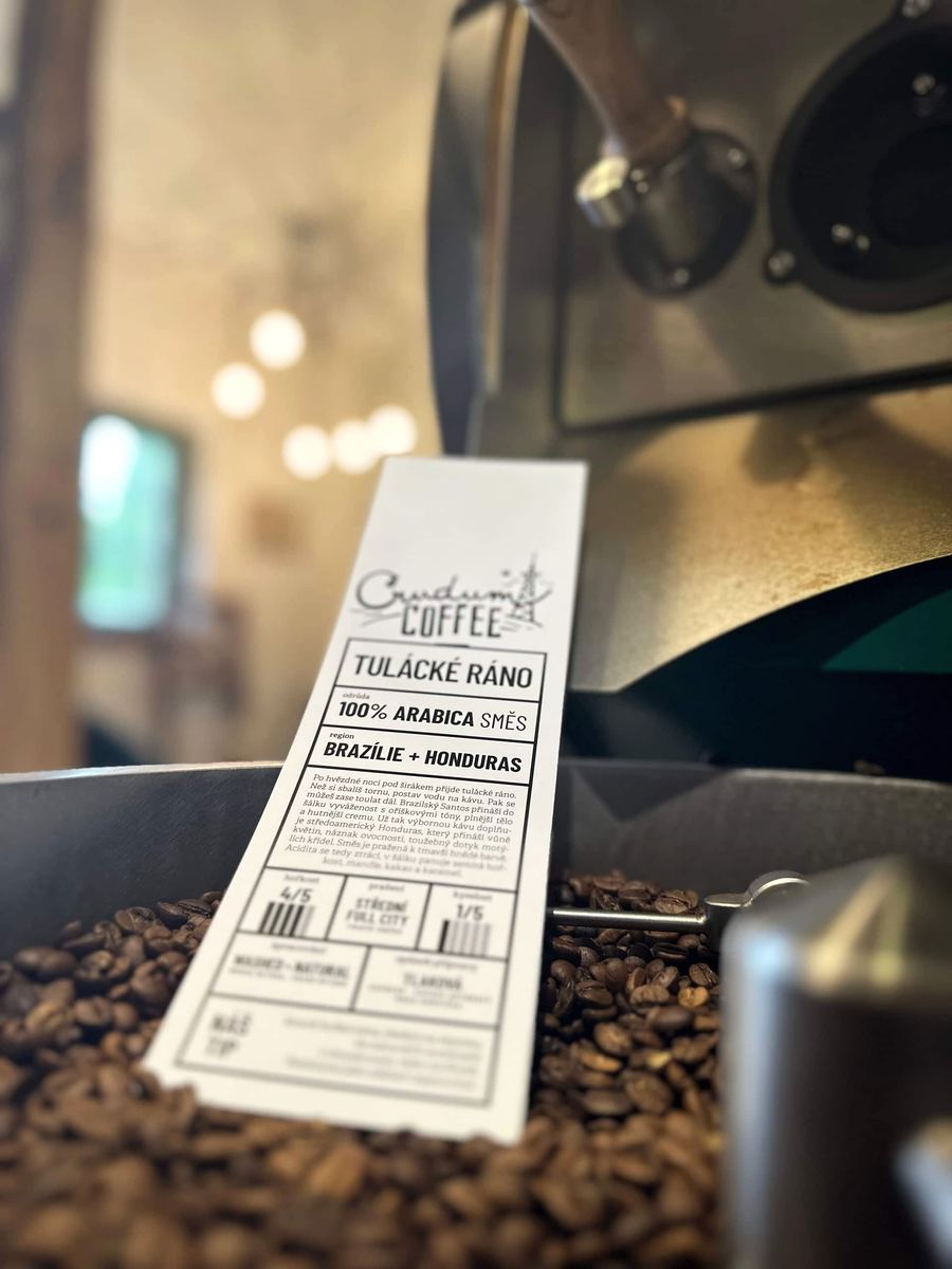 Etiketa Crudum Coffee zapíchnutá v pražených zrnech